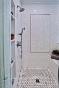 Modern walk-in shower with white subway tile, hexagon floor, and built-in shelving