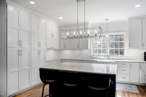 Minimalist white kitchen with black island chairs and modern linear chandelier