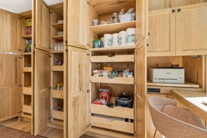 Open custom wood pantry cabinets with pull-out drawers and appliance station